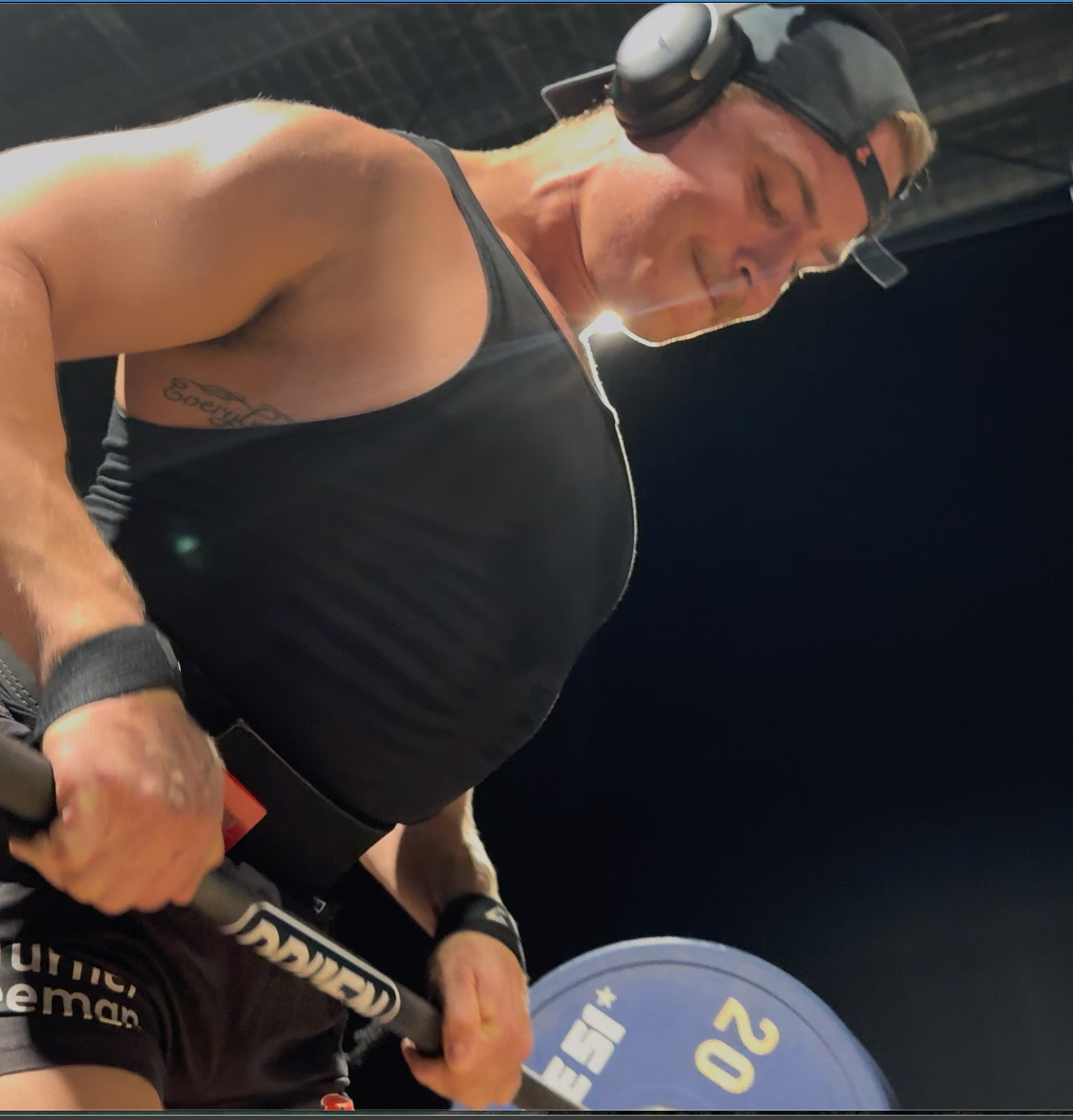 DRIVEN Athletica Member lifting weights with a barbell on a dark background